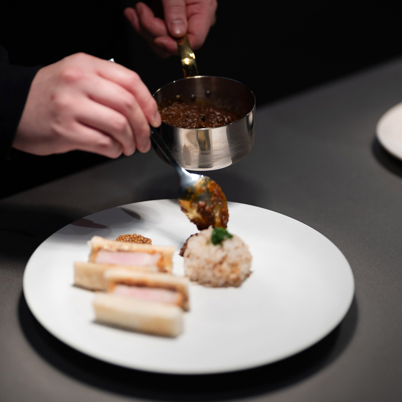Pouring sauce over the dish.