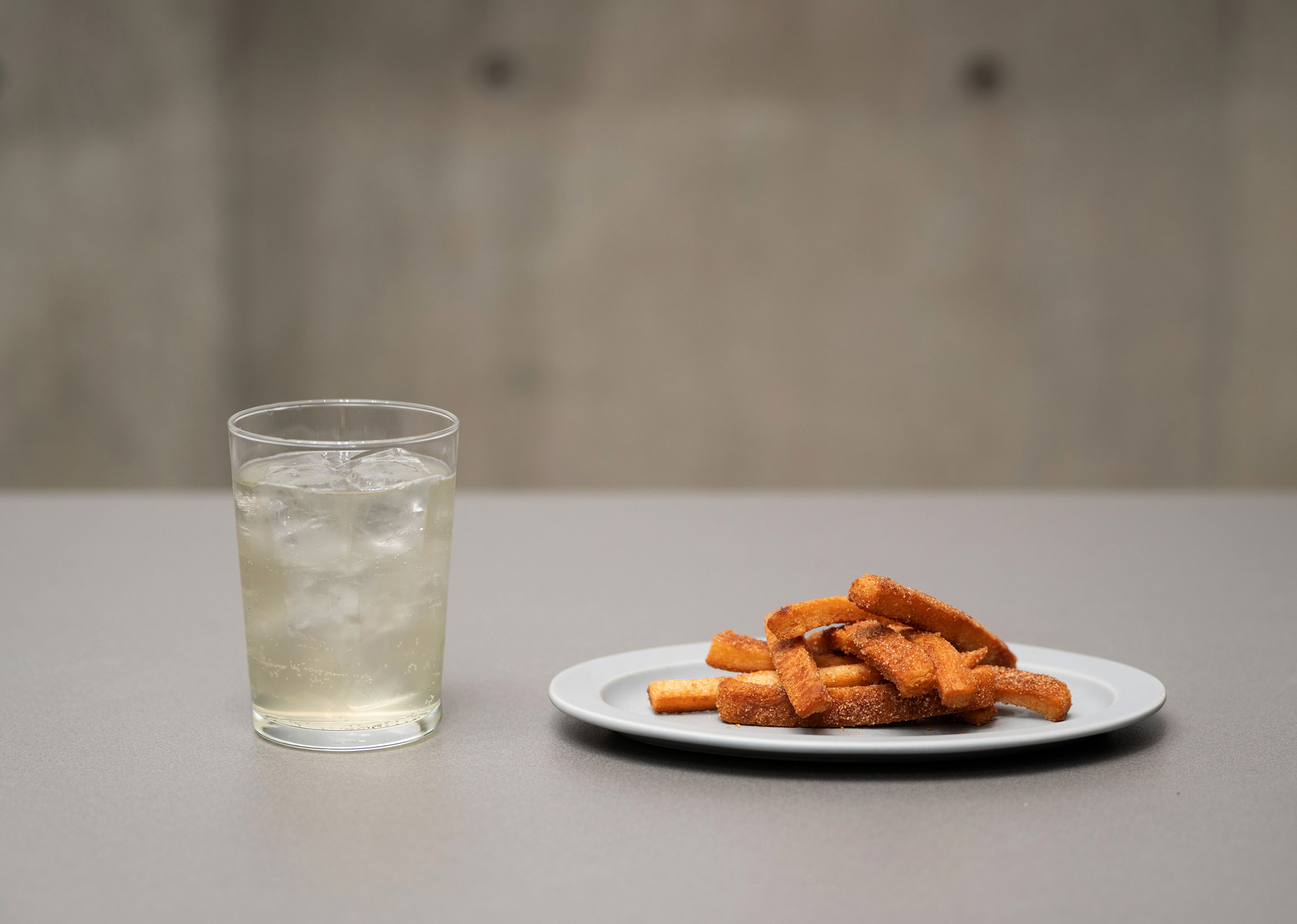A photo of a drink in a glass and fried bread crusts on a plate.