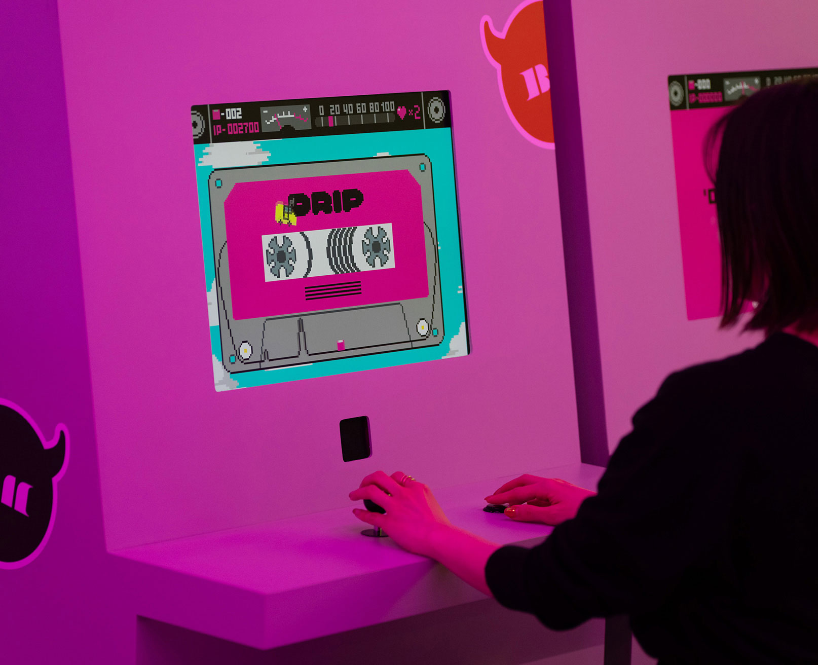 Exhibit. A visitor interacts with a game terminal showing a cassette tape-style graphic on the screen.