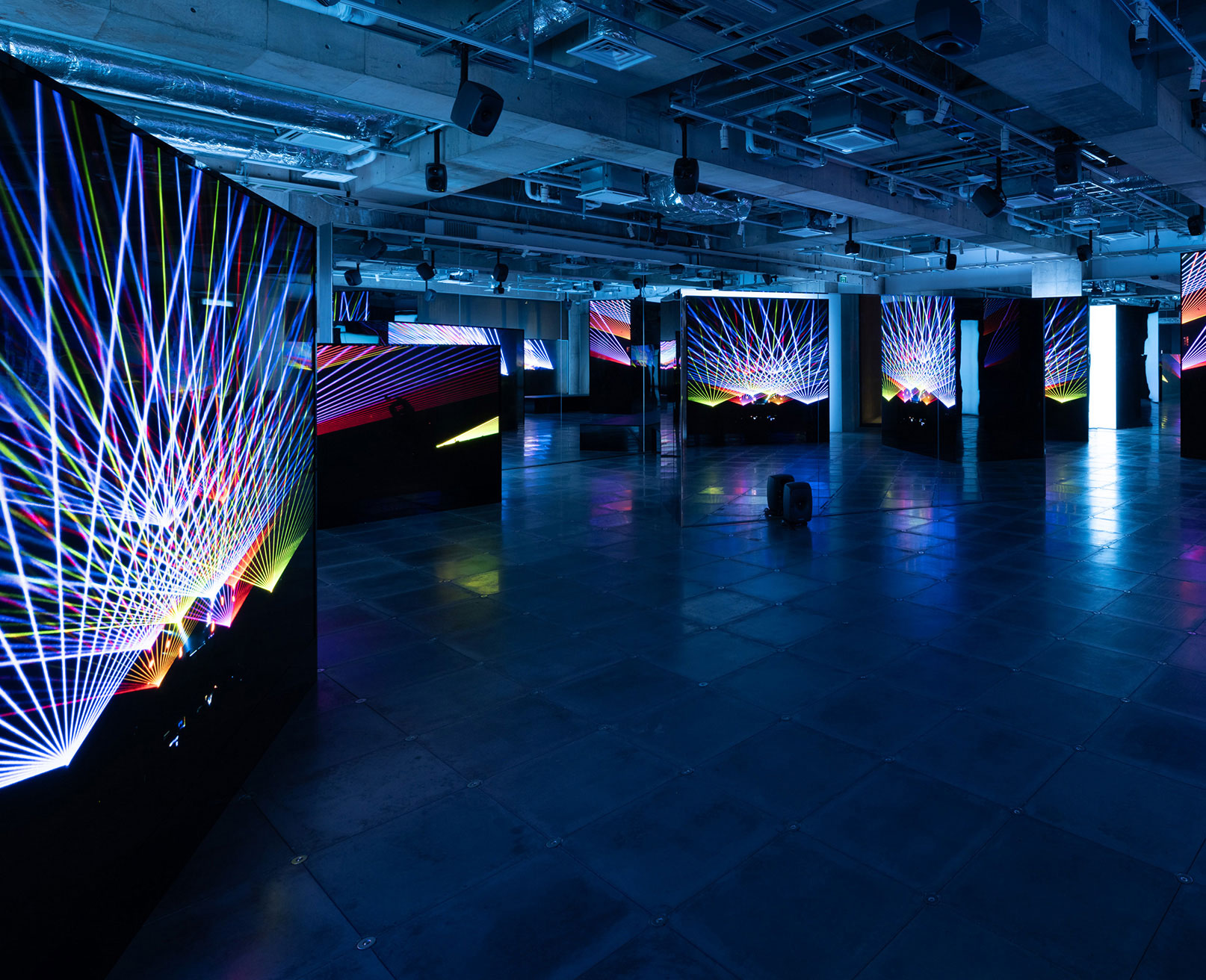 Exhibit. In a dark space, vivid laser graphics are projected onto large screens.