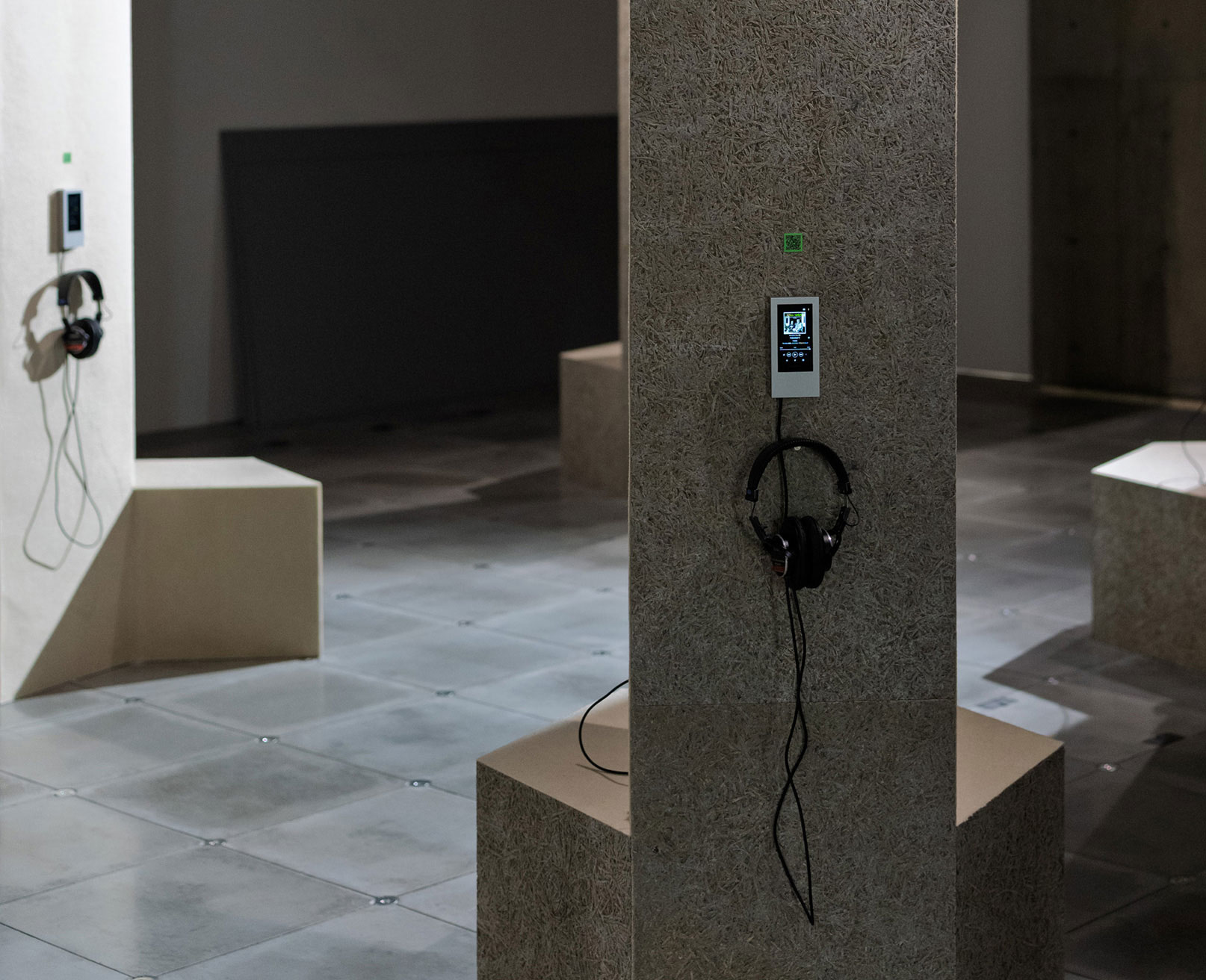 Exhibit. A Walkman mounted on a pillar displays music information, with a pair of headphones hanging below.