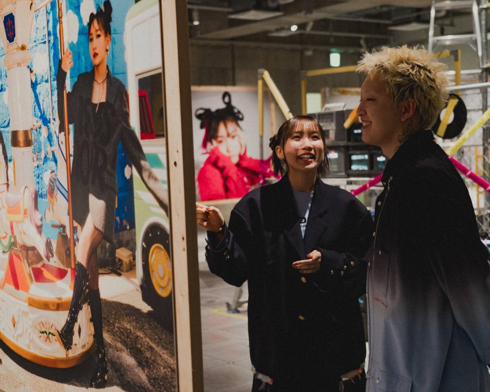 A hands-on experience. The two members of YOASOBI looking at the photos displayed in the exhibit space.