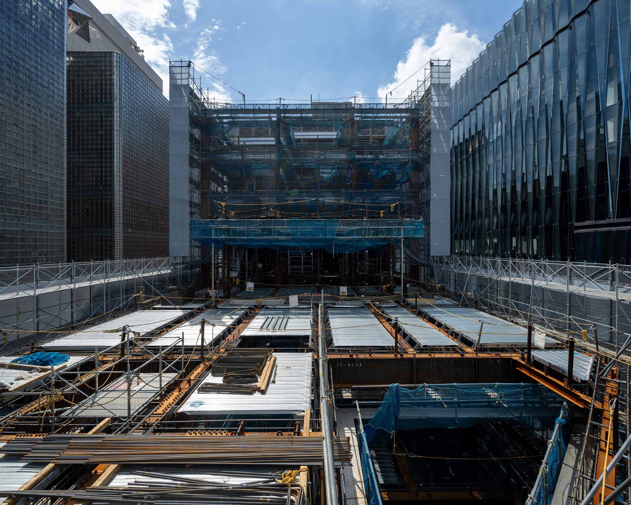 Exterior. Construction site for the building frame on the rooftop floor, surrounded by scaffolding, prior to concrete pouring. The floor shows the exposed steel frame and deck.