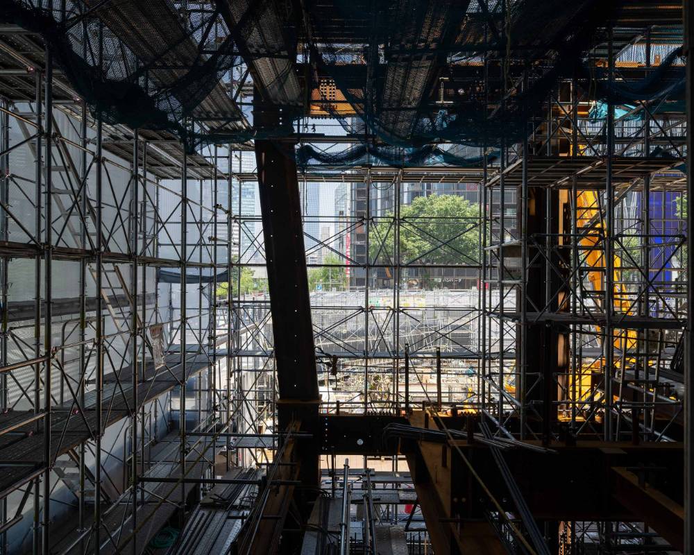 Interior. The city of Ginza as seen from the inside of the above-ground portion of the construction site. The steel frame on the left side has been constructed at an angle.
