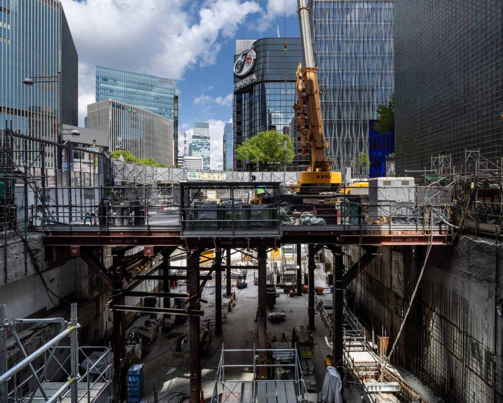 Exterior. Construction for the underground building frame, as seen from the Tokio Marine Nichido Building side. The construction crane sits on top of a platform that extends from deep underground.