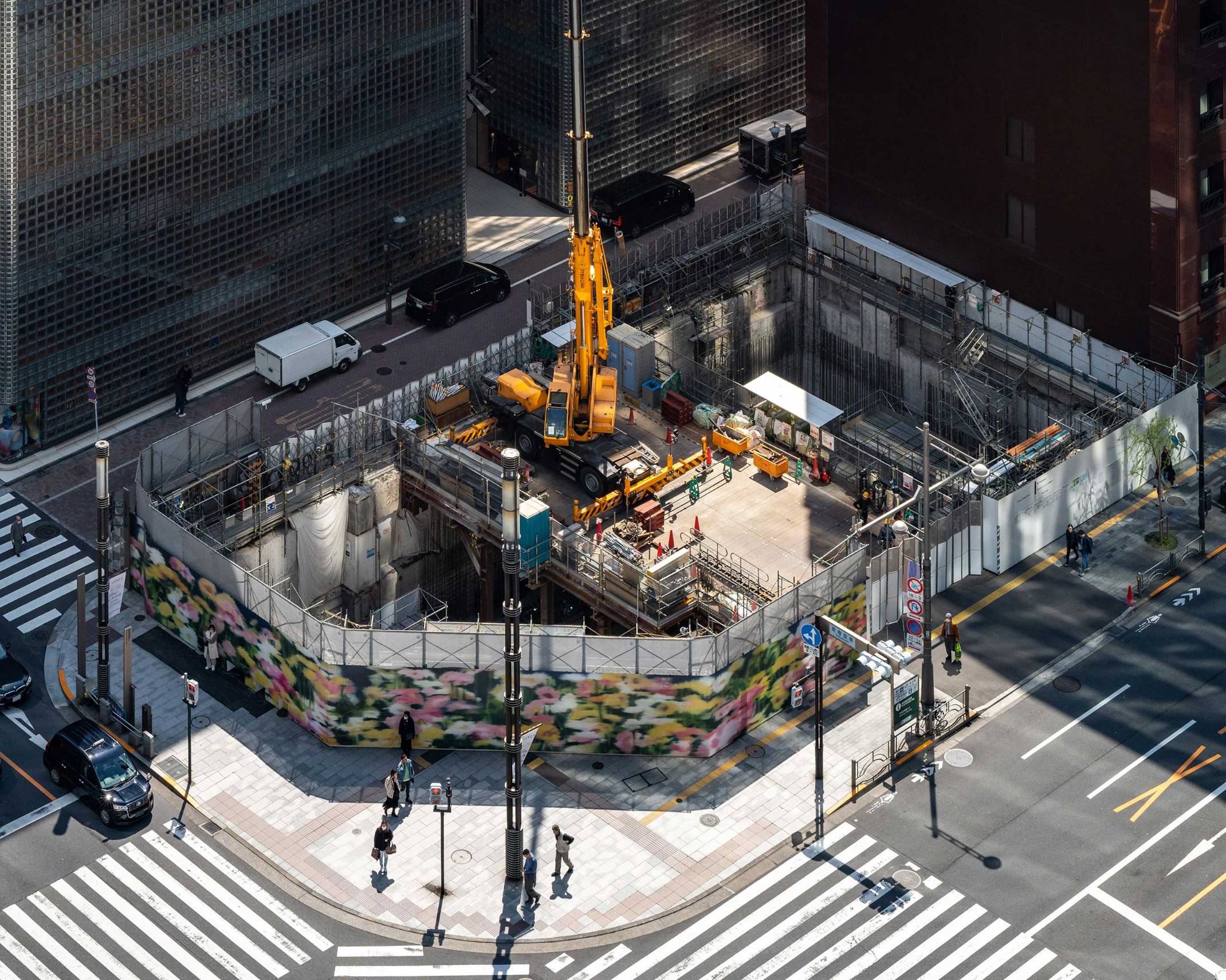 Bird’s eye view. A construction crane sits on top of the platform installed in the center of the deep hole created during the underground construction process for Ginza Sony Park, surrounded with its temporary construction fence.