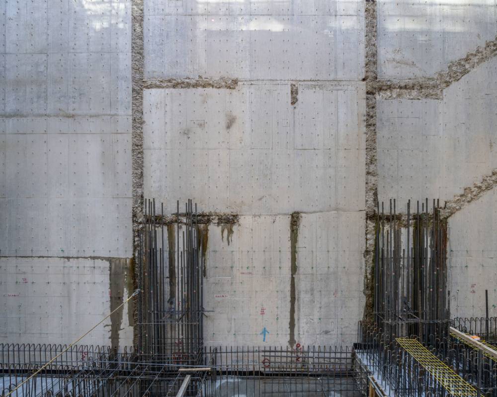 Interior. Exterior basement wall during the construction process; groundwater seeps out from the gap between the new and old building frames.