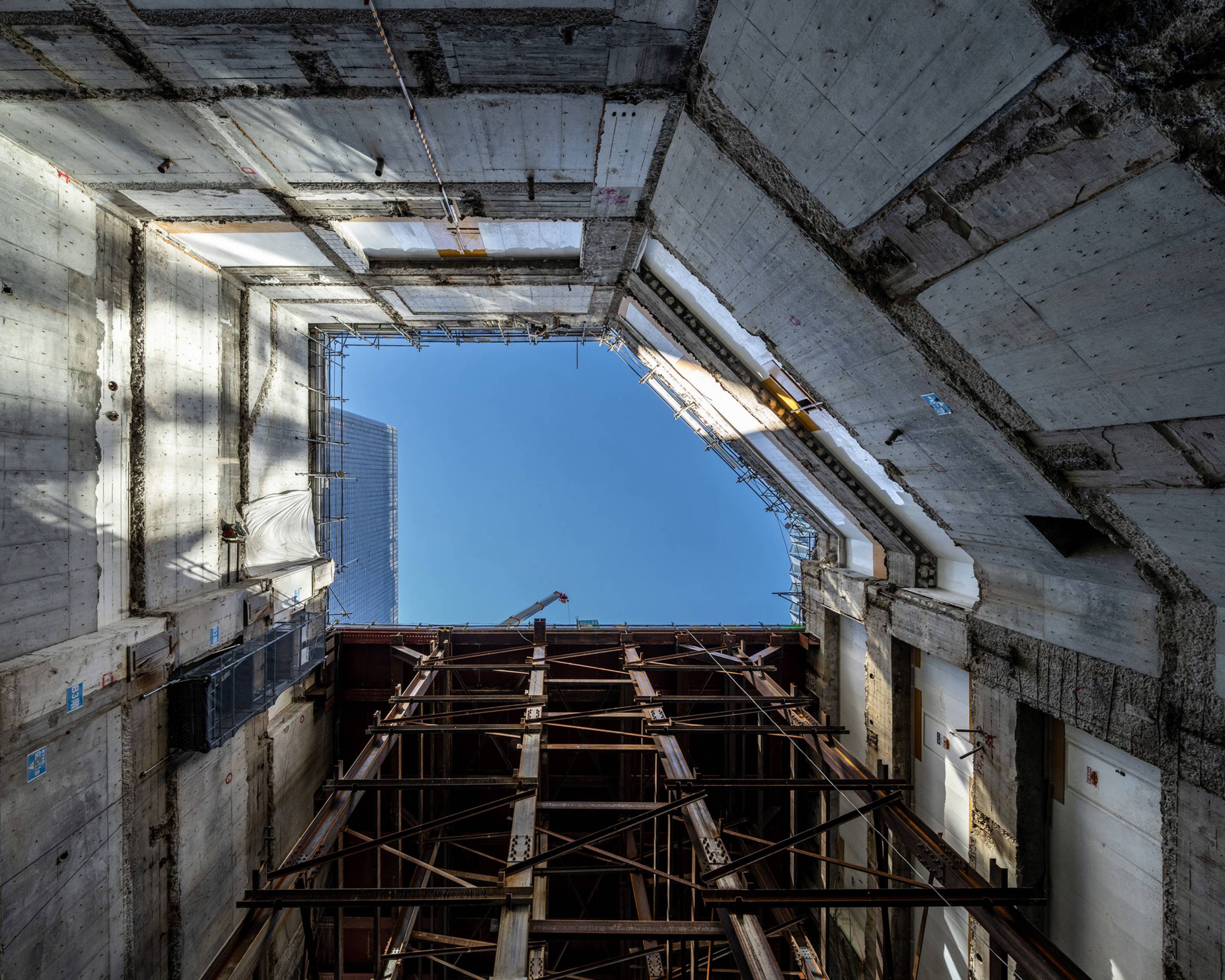 Interior. Sky as seen from deep underground, ringed by the exterior basement walls and construction platform.