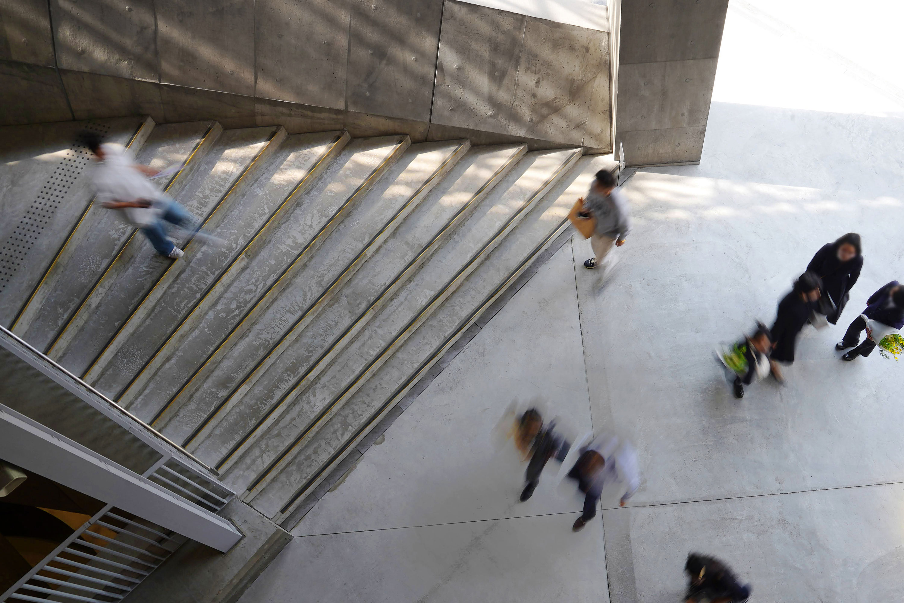 Several people are passing by near the large staircase, seen from above.