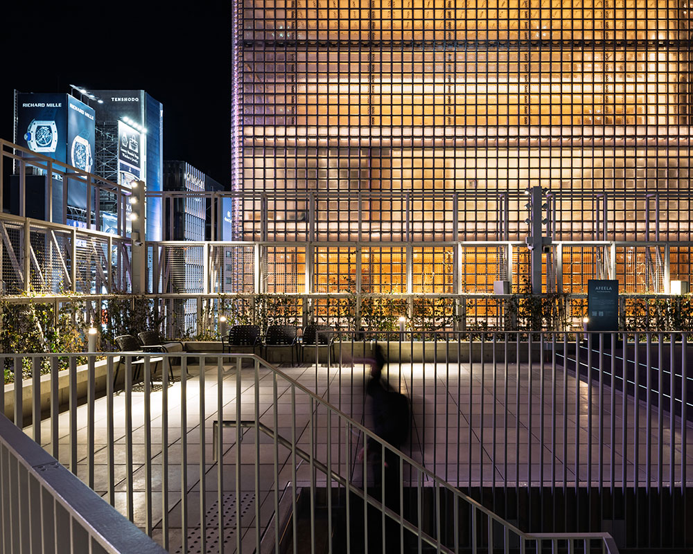Night view from the rooftop. A person is ascending the staircase in the foreground.