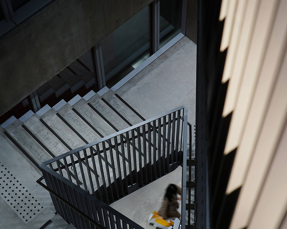 A person is walking at the far end of an open stairwell, seen from above.