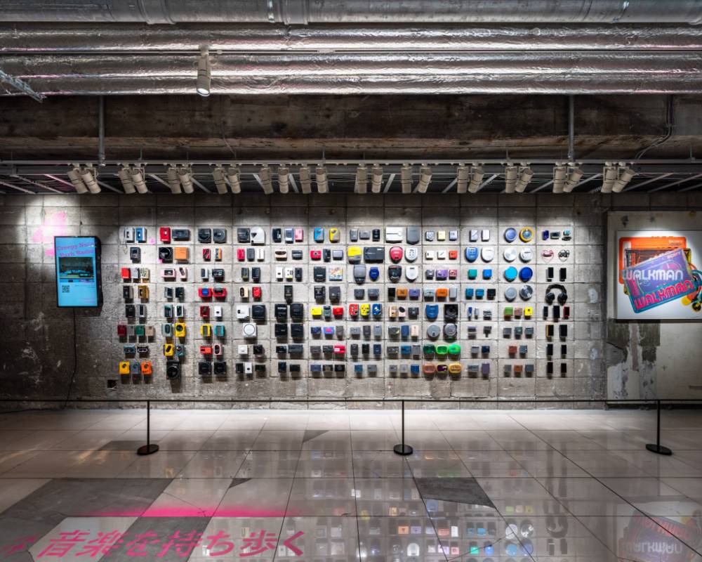 Exhibit item. Many past Walkman models are exhibited on the wall, alongside pieces by Andy Warhol.