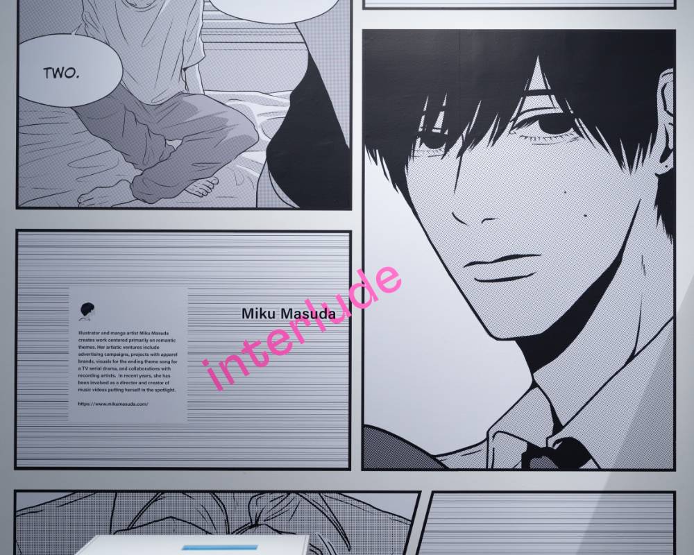 Exhibit. A page with a close-up of a man’s face, from the manga Interlude is exhibited prominently on the wall.