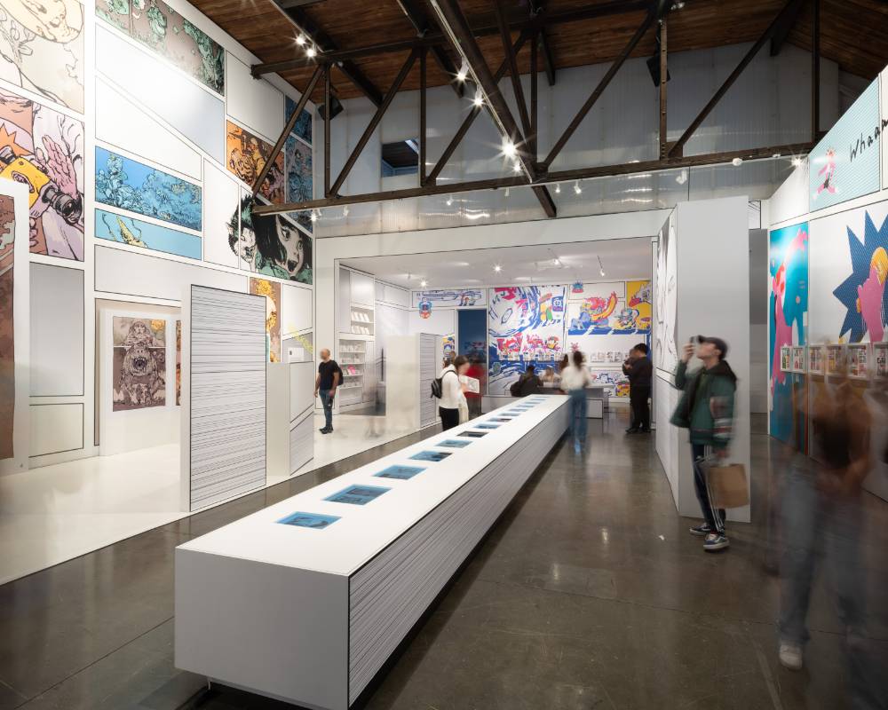 Interior. Visitors gather around a long table placed in the center of the venue, embedded with numerous monitors.