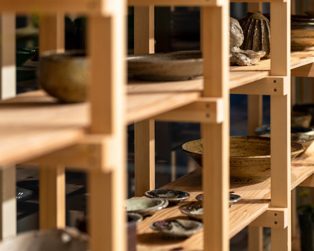 Exhibit. Various ceramic tableware goods, vases, and other items are displayed on the wooden shelves.