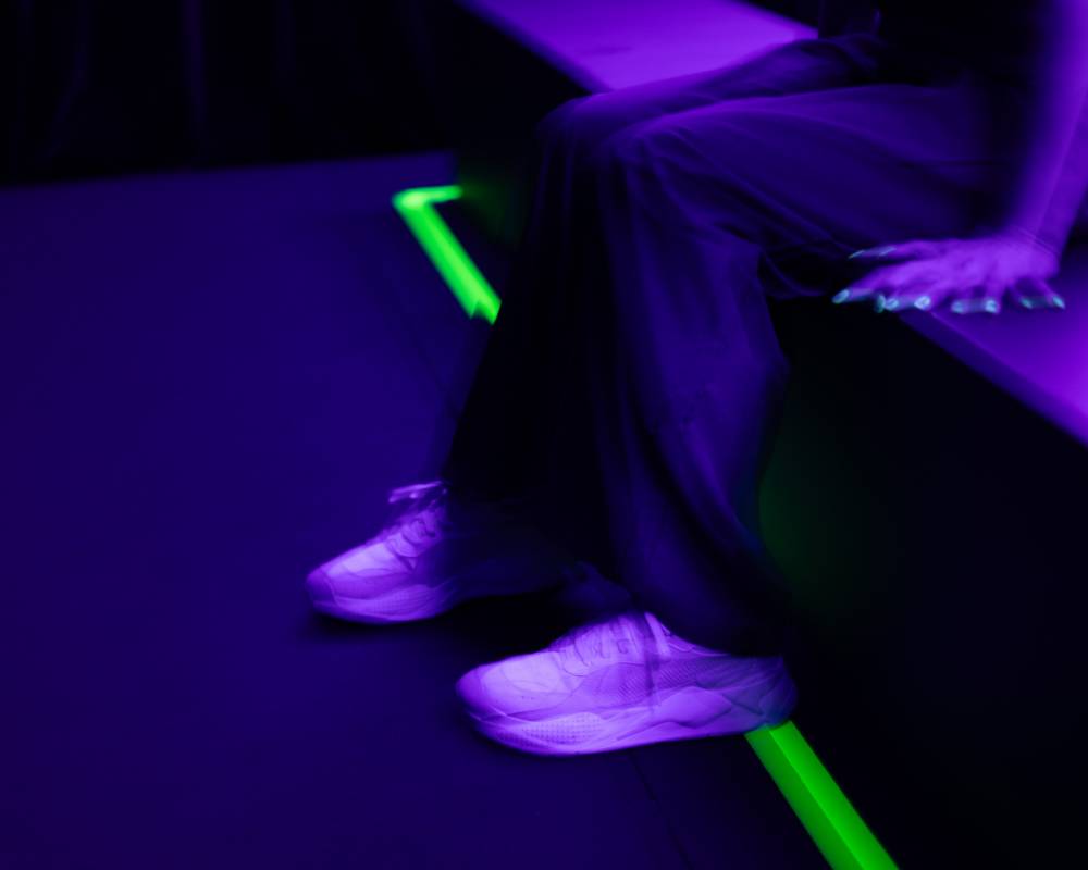 A hands-on experience. A visitor sits on a bench in a dim room lit with purplish light, the area around their feet vibrating.
