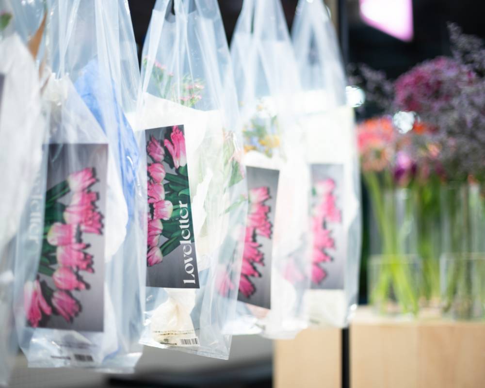 Exhibit. Several clear shopping bags containing cards with flowers and key visuals are hung up.