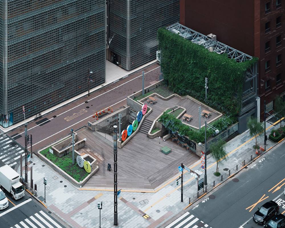 Sony Park Exhibition, exterior view. Six round art objects, labeled “1” to “6” respectively, are lined up in a row on the ground floor. People walk on the adjacent sidewalk.