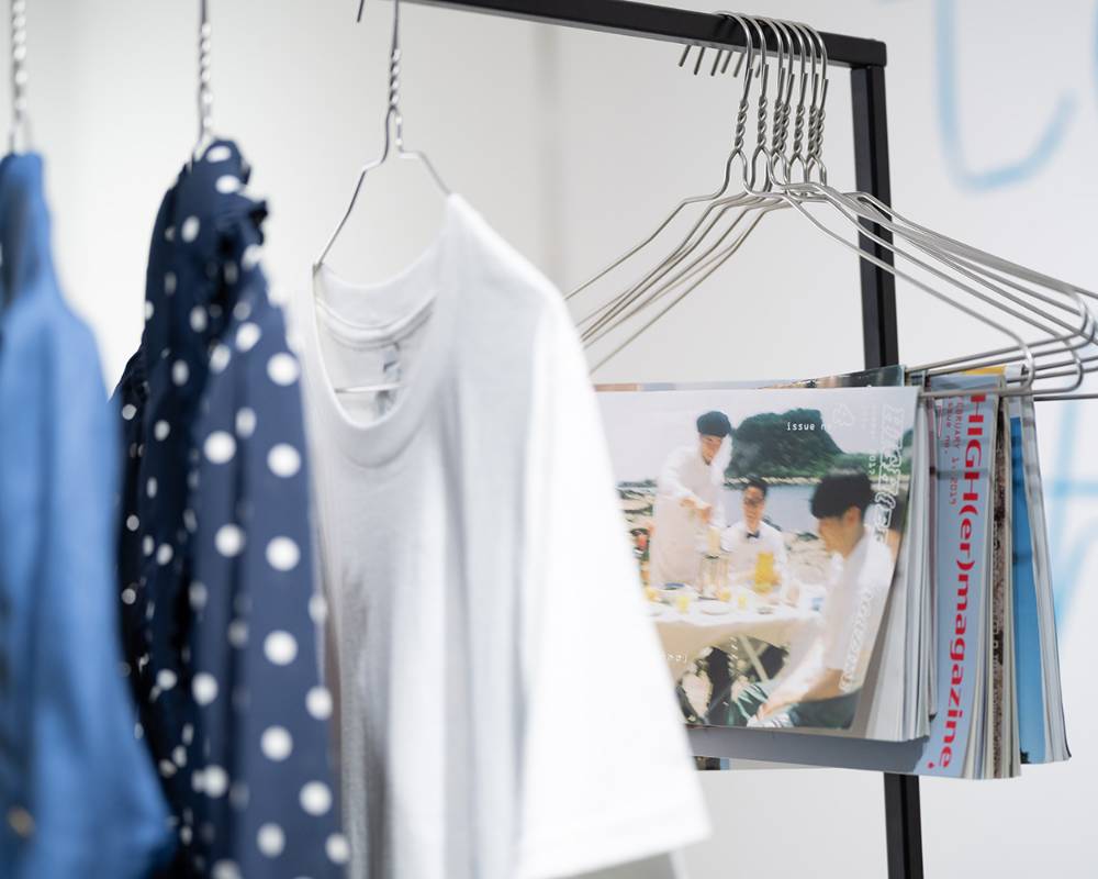 Exhibit. Hanging on the hanger rack are clothes and magazines on hangers.