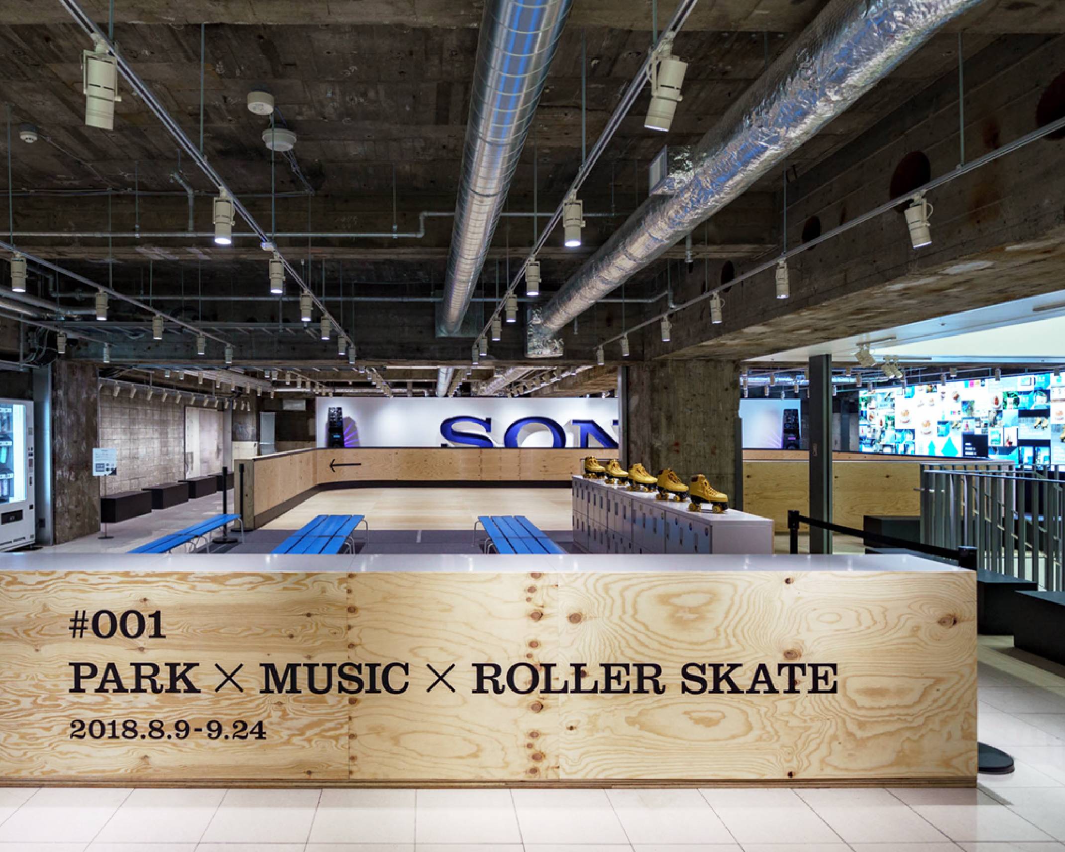 Exhibit. At the back of the roller skating rink, made of wooden planks, is a sign that says “SONY.”