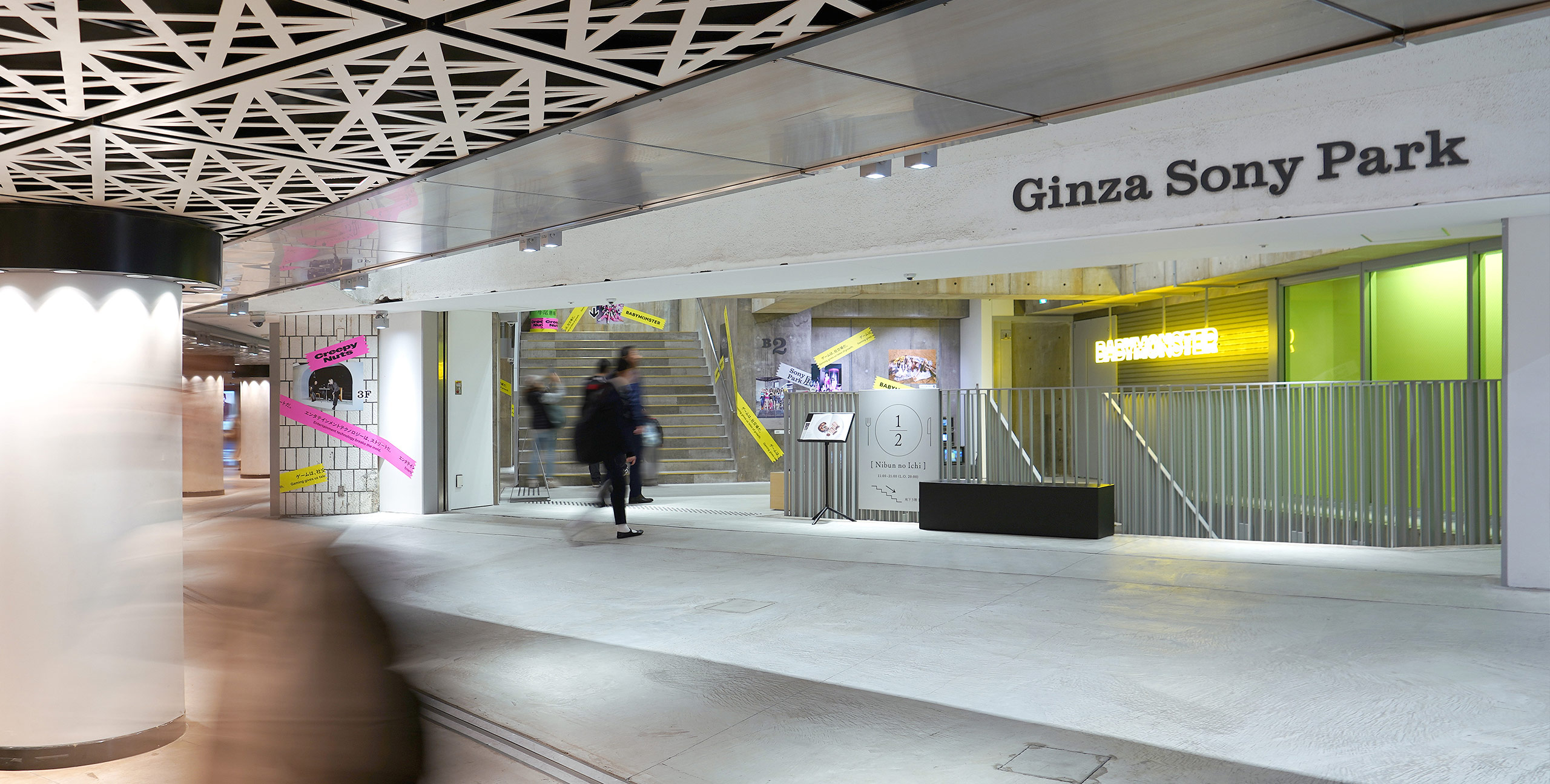 Entrance to Ginza Sony Park seen from the underground concourse. The ceiling features a geometric pattern, and the walls are decorated with “Sony Park Exhibition” signage and artist visuals.